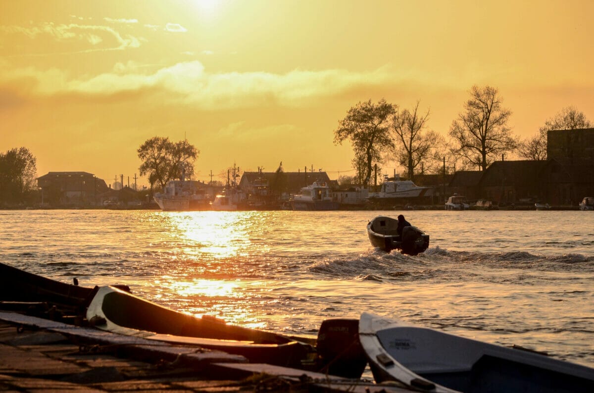 Imagine din Sulina cu o barca pe Dunăre, la apus de soare.